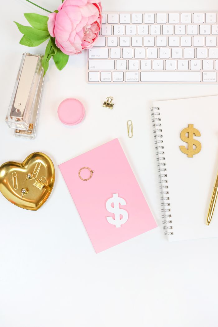 A chic workspace featuring a white keyboard, pink notepad, and gold accessories.